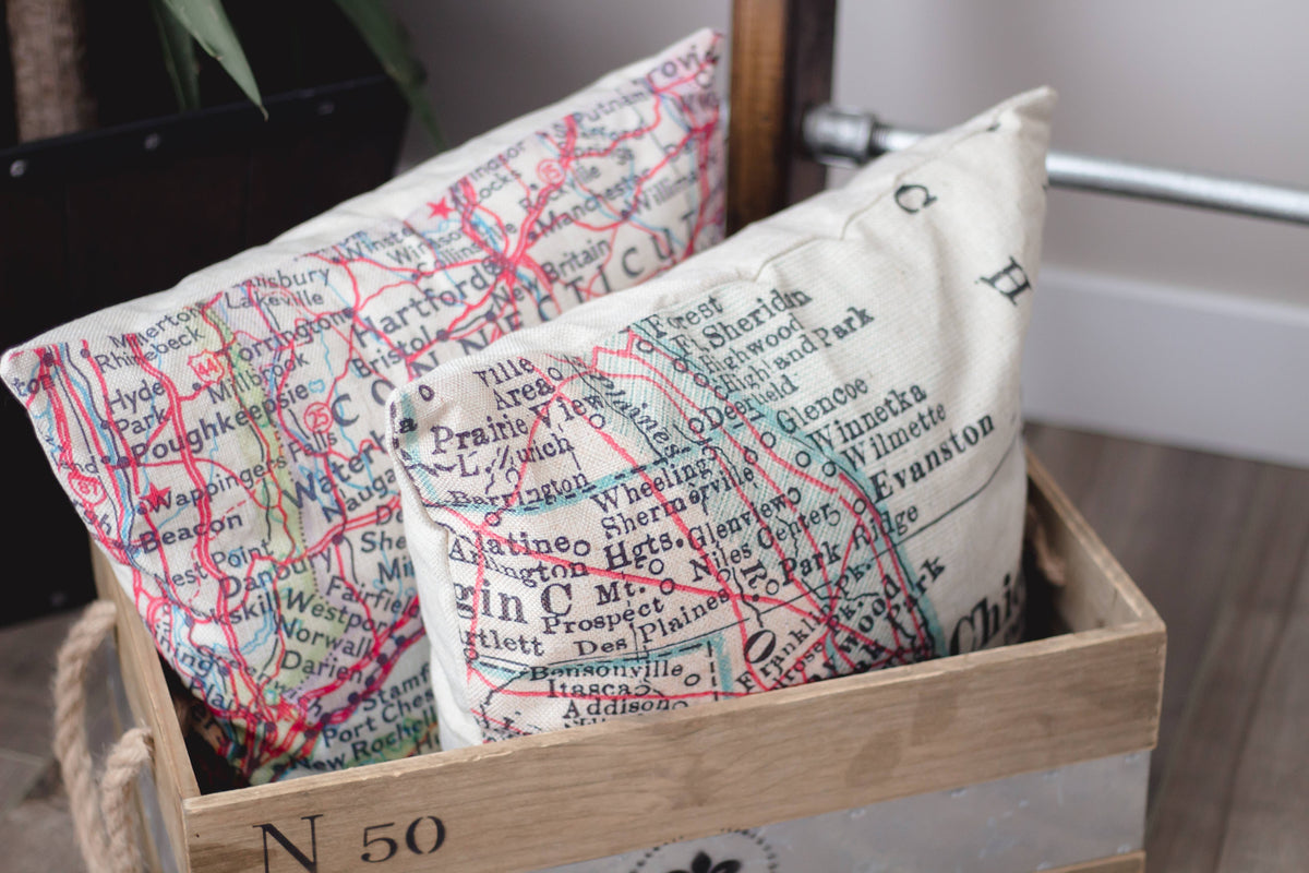 Vintage map pillows in a wooden crate