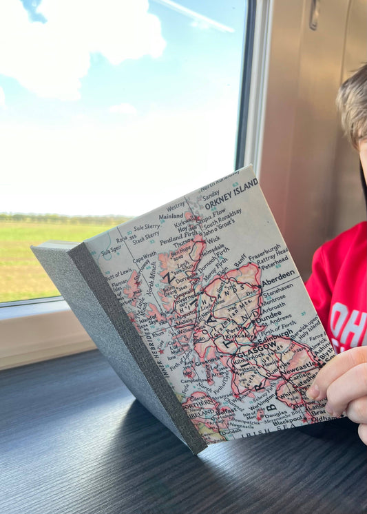 Reading a vintage map journal on a train