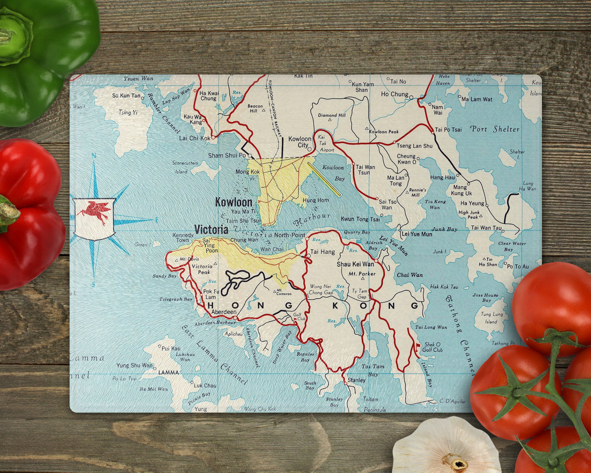 Hong Kong glass cutting board featuring a 1959 vintage map of Hong Kong Island Kowloon and Victoria Harbour on a wooden surface surrounded by vegetables
