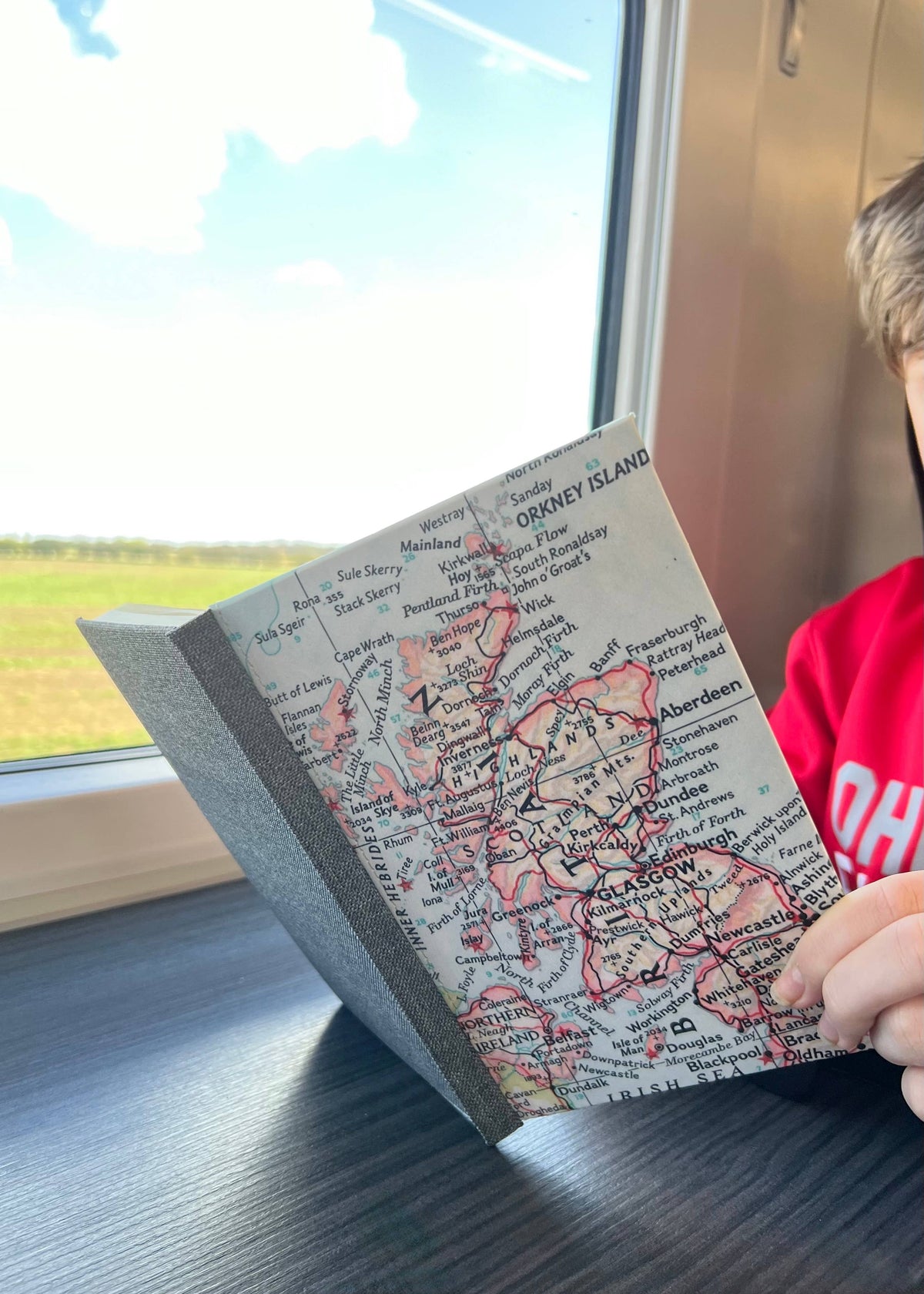 Reading a vintage map journal on a train